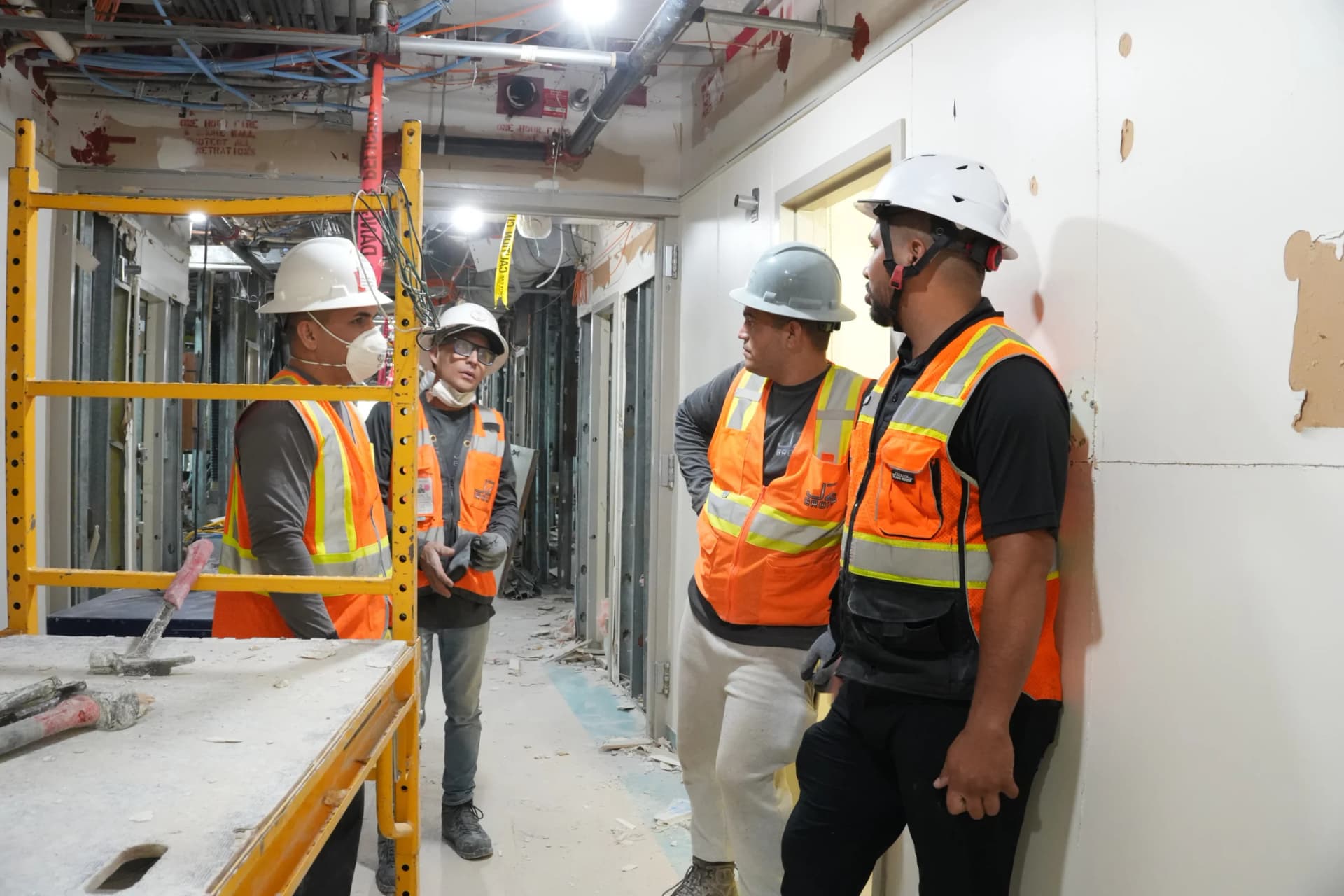 Four JZ crew members discussing work beside a scaffold at the UHealth Tower penthouse